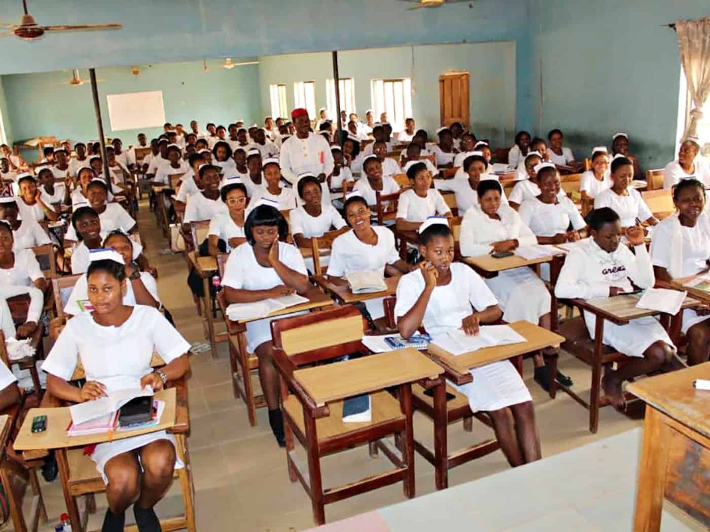 Cameroonian nursing students in white uniforms studying in a classroom