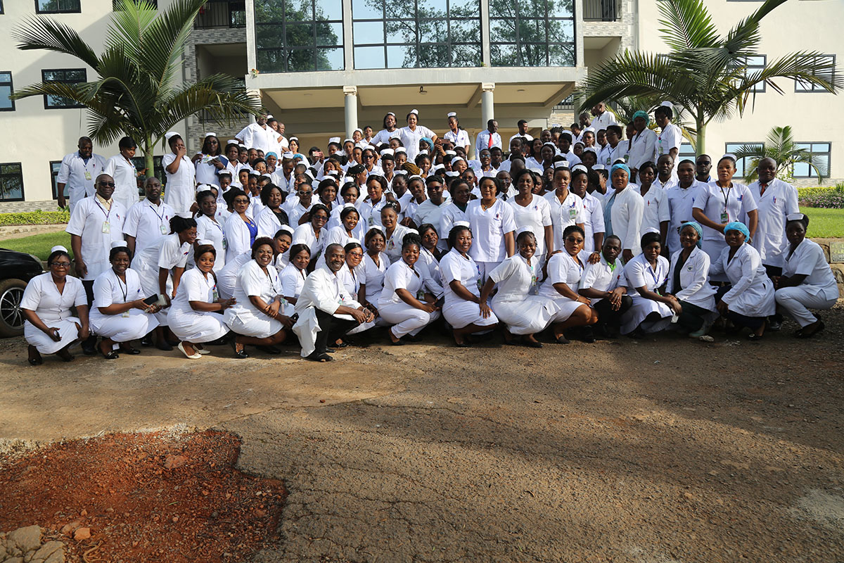 Large cohort of Cameroonian nursing students and faculty in white uniforms outside campus