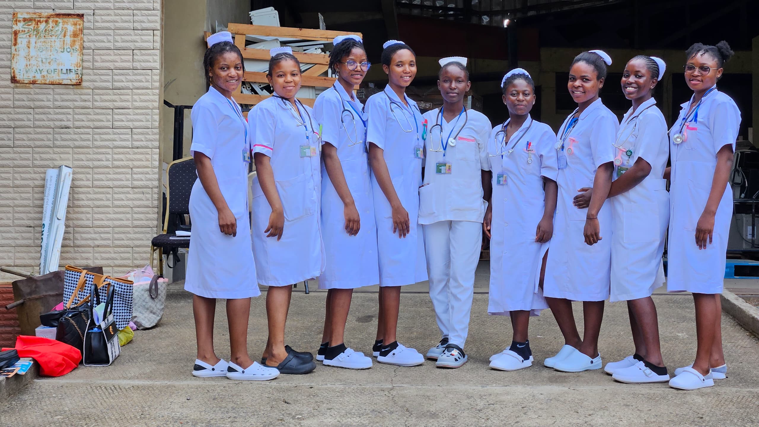 Cameroonian nursing students in white uniforms with nursing caps and stethoscopes standing together